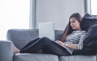 A Woman Lying on a Couch and Working from Home