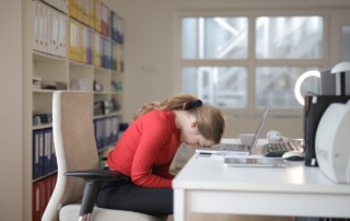 A Woman resting her forehead on a laptop