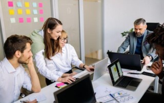 A team of colleagues working together in an office while discussing employee benefits plans